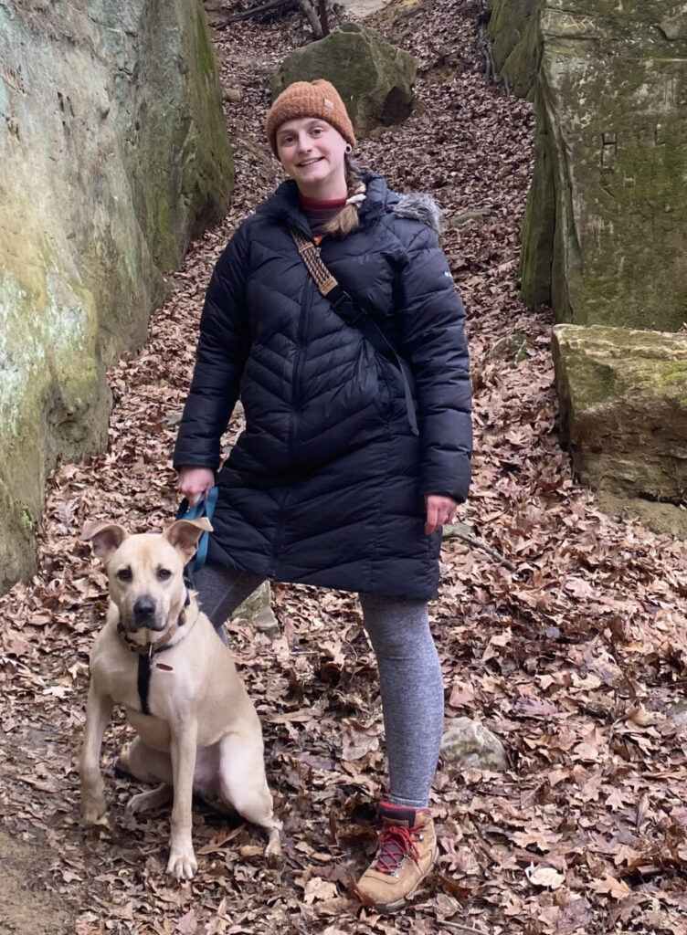 Dayna and her dog hiking between two massive boulders