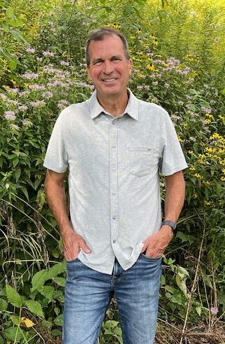 Joe Gates standing in front of wildflowers