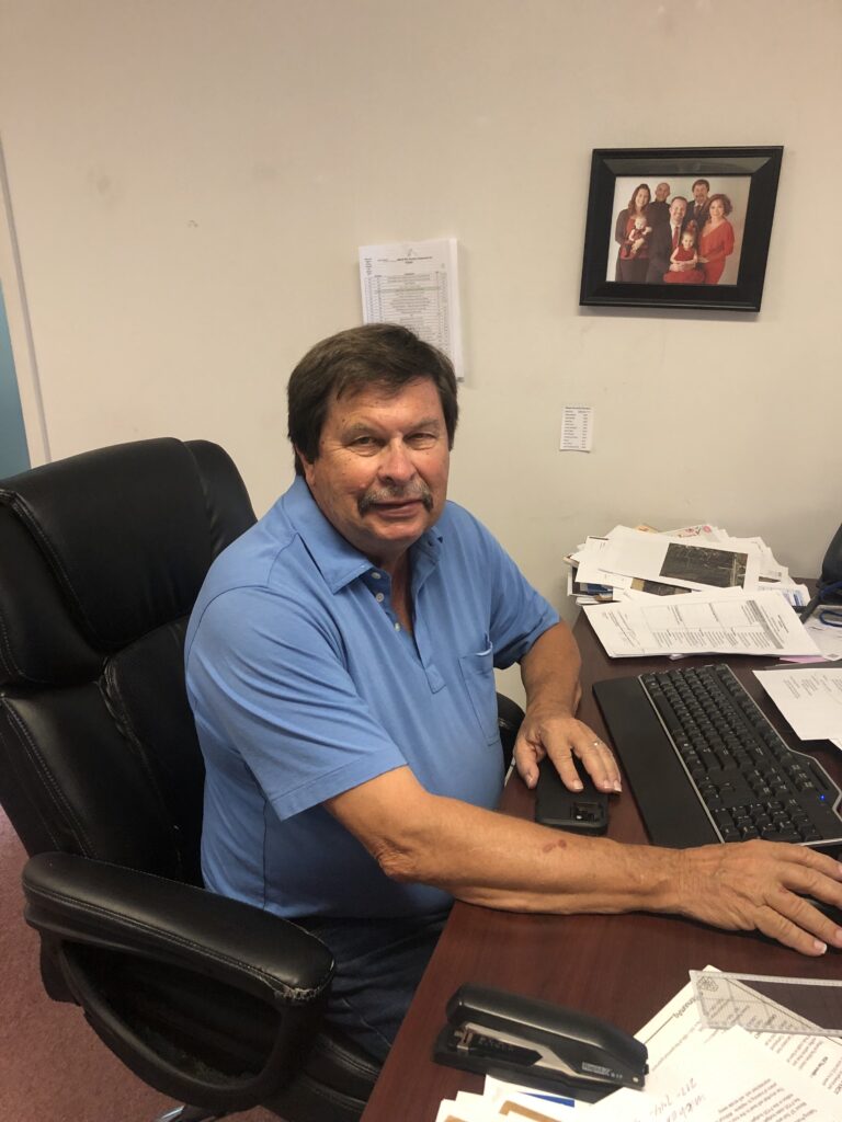 Rich sitting at his desk dressed in a blue shirt